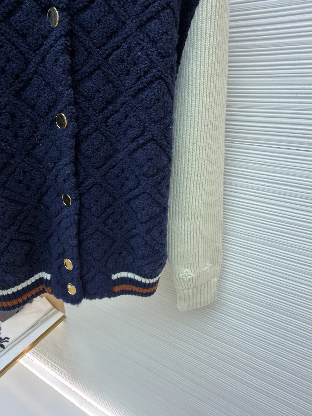 LOUIS VUITTON SKI ski series color-blocked striped baseball long-sleeved jacket ●Original version: purchased and developed for 22999 ●Item number: 1682091-D35 ●Fabric: wool blended fabric ●Technology: knitted ●Color: blue and white ●Version: fitted version ●Weight: about 1070 grams ●Size: S-M-L-XL ●Description: This Louis Vuitton color-blocked knitted cardigan uses a three-dimensional cable knitting process to create the main body. It uses high-count merino wool blended fabrics and uses a double needle bed knitting machine to create a concave and convex rhombus texture. The knitting density reaches 32 needles per square centimeter, making the texture both three-dimensional and soft. The main body of the body is made of navy blue fixed-spun yarn, which has been washed and fixed three times to effectively prevent fading. The sleeves are made of off-white vertical pit rib knitting, and the single-strand yarn twist is controlled at 800 twists/meter to ensure resilience and fit. The metal snaps are made of custom-made brass and have been treated with gold-plated glaze sealing. The contrasting ribs on the collar and hem are intarsia woven, accurately matching the proportions of the brand's classic three-color webbing. The cuffs also have a hidden laser-engraved brand logo. The overall process combines traditional knitting techniques with modern precision, and the details are full of craftsmanship. The overall wiring is straight and delicate, the fabric is comfortable and soft, and the color is consistent without color difference. It can be matched with the same style to create a fashionable look and control various occasions. Customized accessories, complete with three standards, same style for men and women!